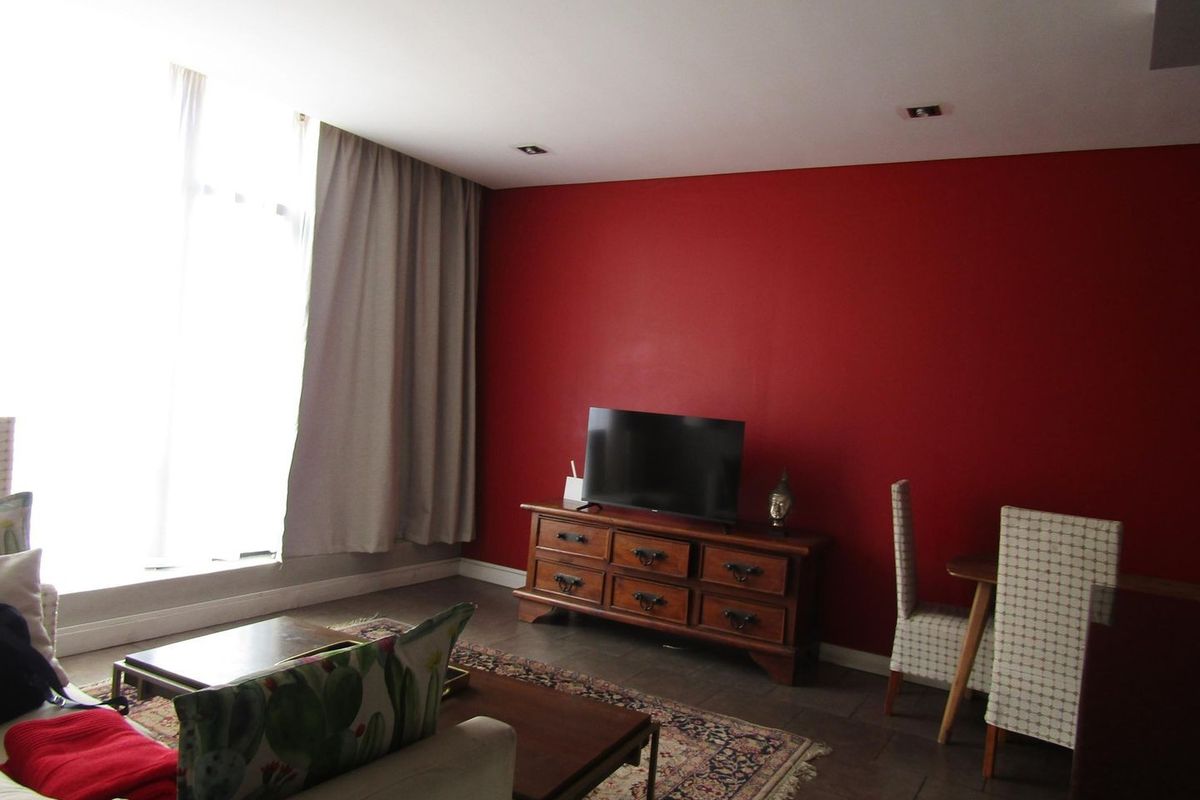 A living room featuring tiled flooring, recessed downlights, and a large window allowing for natural light.