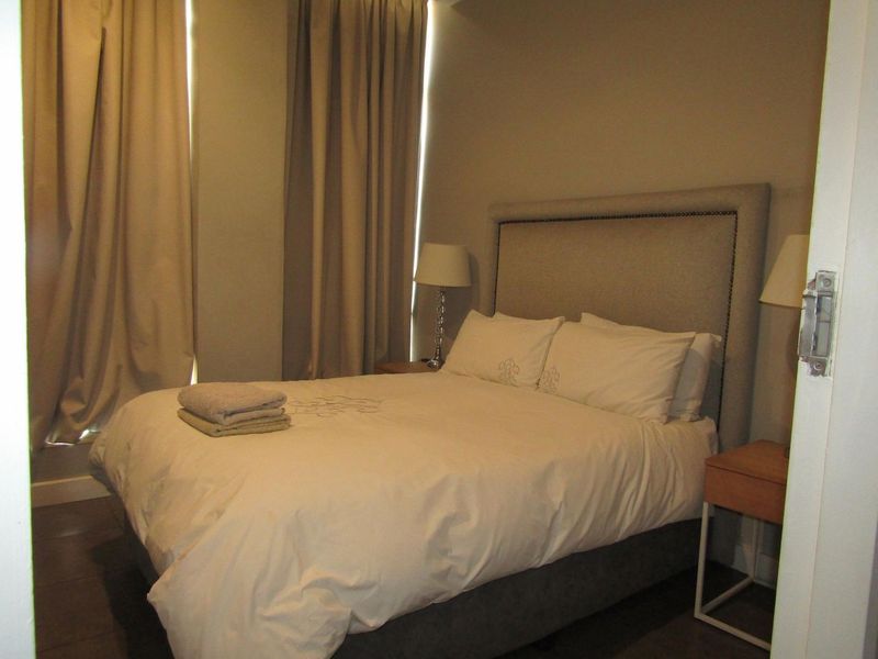 A standard bedroom featuring neutral wall tones, tiled flooring, and floor-to-ceiling curtains, providing a functional and comfortable sleeping space.