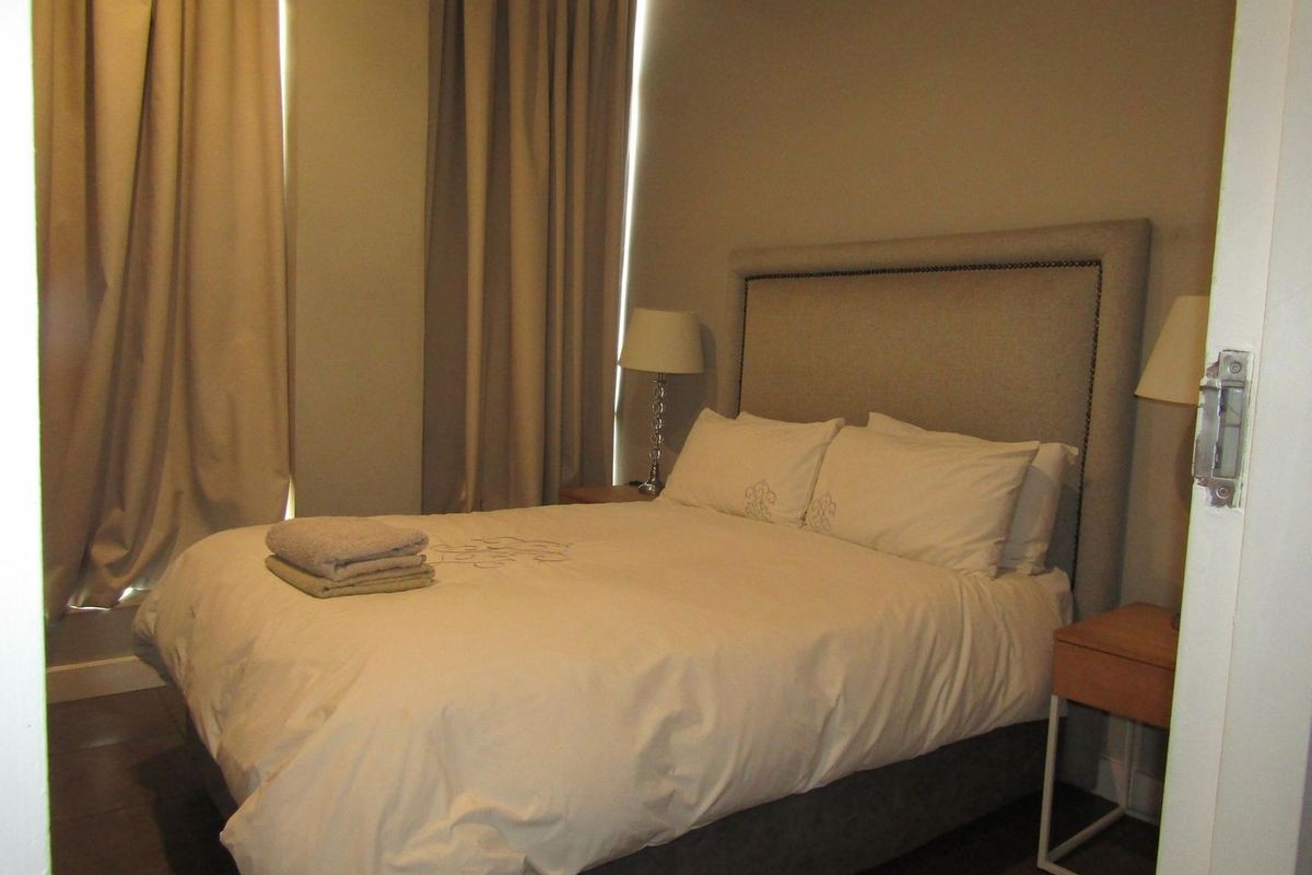 A standard bedroom featuring neutral wall tones, tiled flooring, and floor-to-ceiling curtains, providing a functional and comfortable sleeping space.