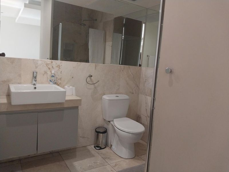 Modern bathroom featuring stone wall and floor tiles, a vessel sink with vanity cabinet, and a glass-enclosed shower area.