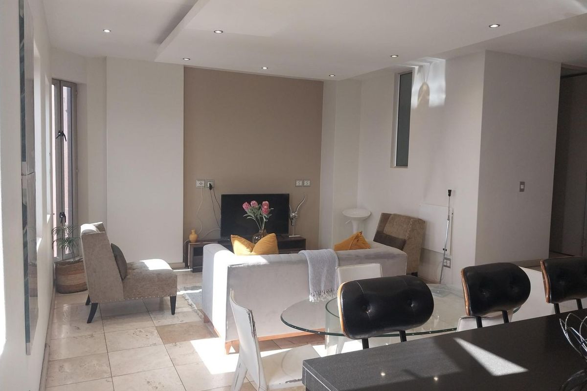 An open-plan living and dining area featuring tiled flooring, recessed ceiling lighting, and a modern dropped ceiling design.