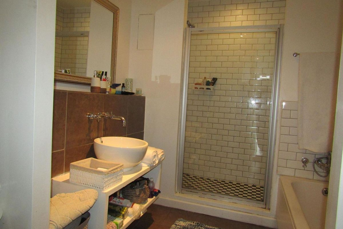 A functional bathroom featuring a vessel sink with wall-mounted faucet, a separate shower enclosure with subway tiling, and a built-in bathtub.