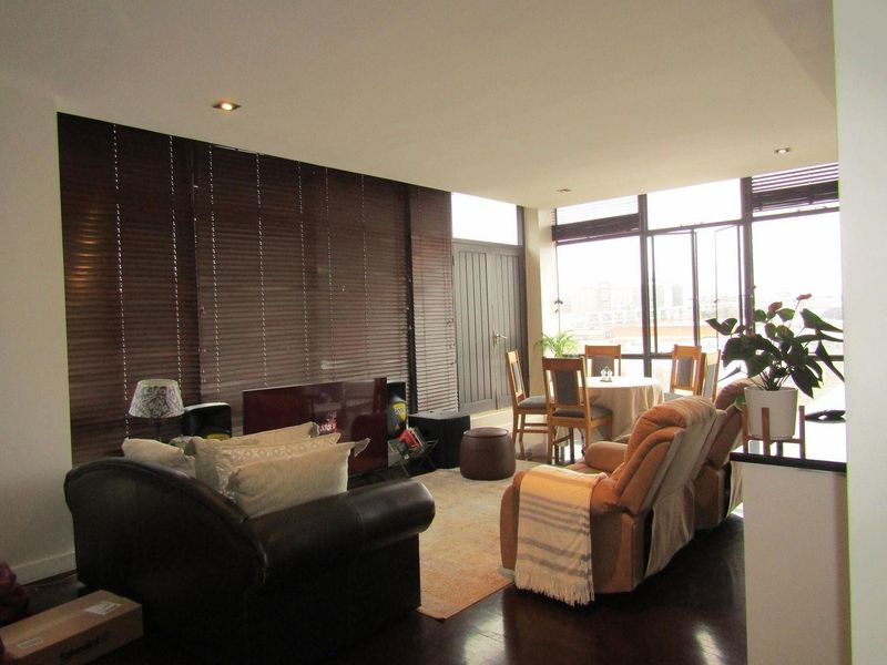 Spacious open-plan living and dining area featuring dark timber flooring, recessed lighting, and expansive windows that provide ample natural light.