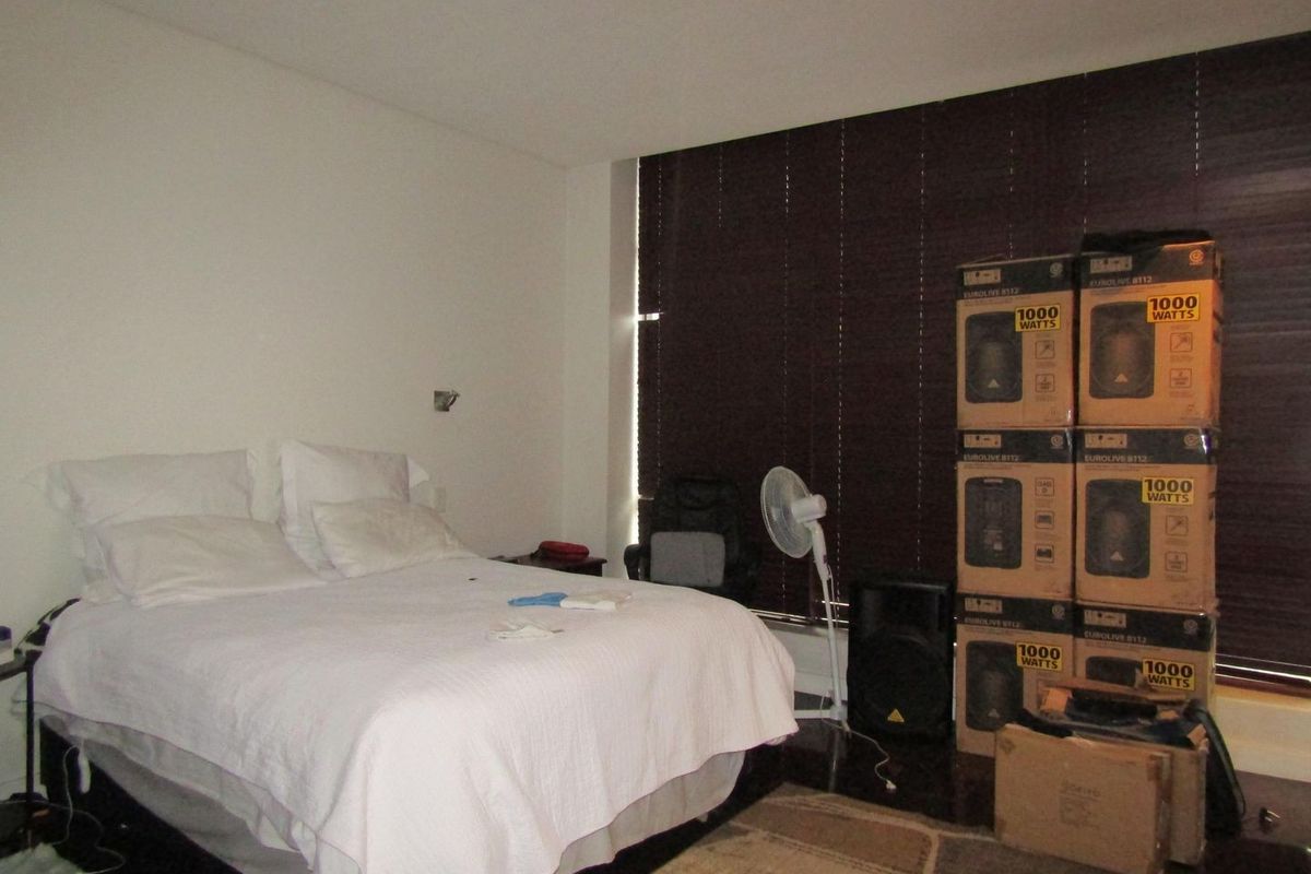 A bedroom featuring dark wood flooring, recessed lighting, and venetian blinds, providing a functional space with neutral wall finishes.
