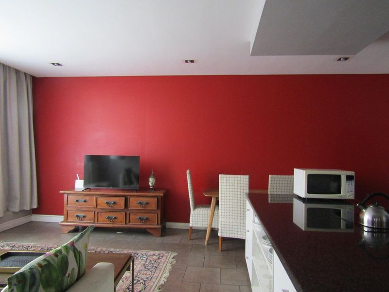 Open plan living and kitchen area featuring tiled flooring, recessed lighting, and a dark granite kitchen countertop.