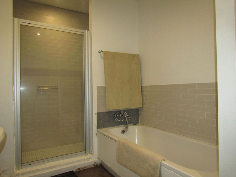 A functional bathroom featuring a shower enclosure and a bathtub with neutral subway tile backsplash and standard fixtures.