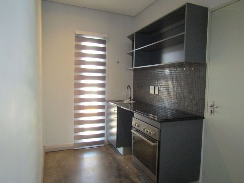 Compact scullery area featuring built-in cabinetry, a stainless steel sink, mosaic tile backsplash, and a built-in oven with hob.