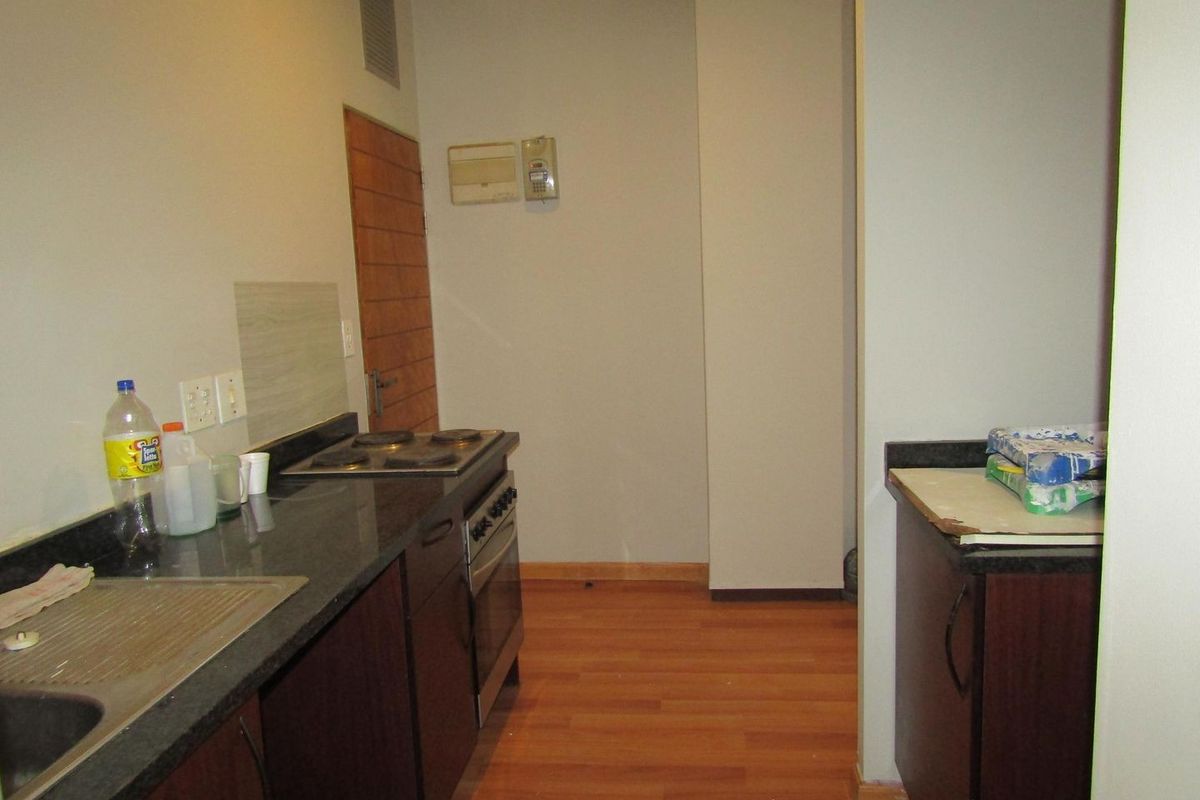 A functional kitchen featuring dark cabinetry, granite countertops, an electric stove, and laminate flooring, providing a practical workspace for daily cooking.