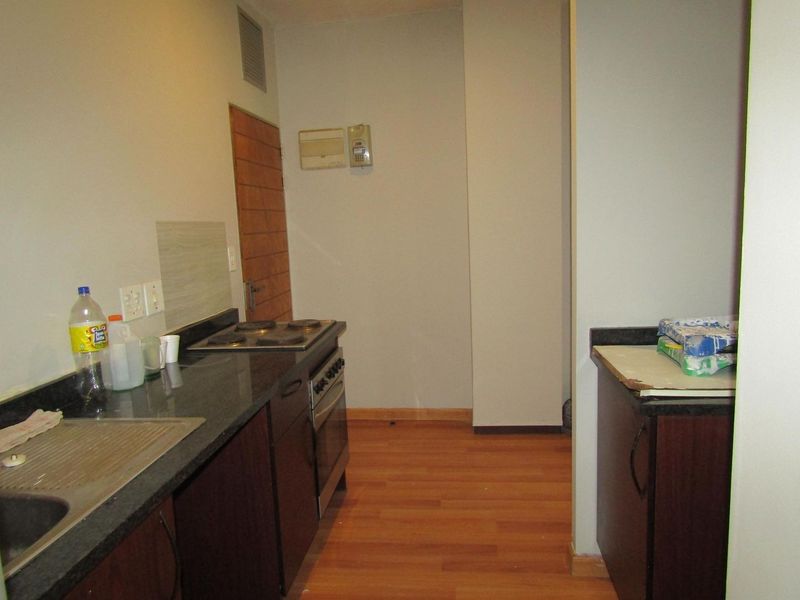A functional kitchen featuring dark cabinetry, granite countertops, an electric stove, and laminate flooring, providing a practical workspace for daily cooking.