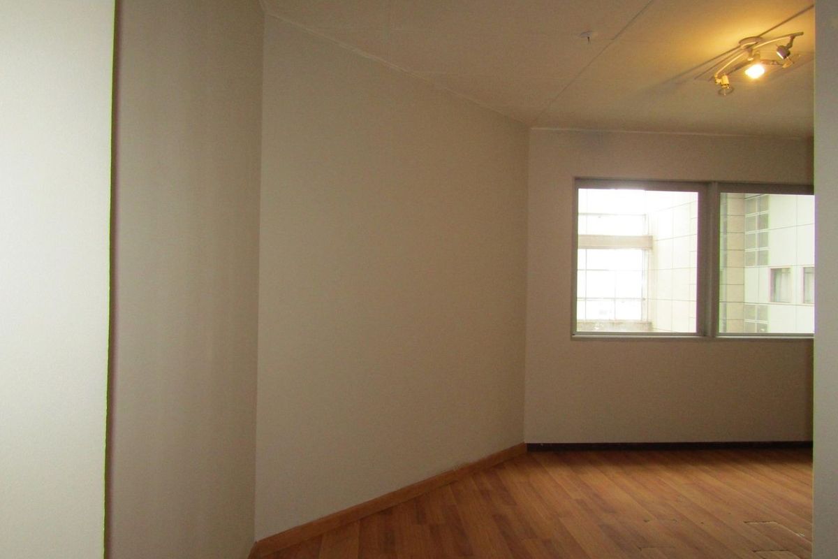 An empty living room featuring laminate flooring, neutral walls, and track lighting, offering a blank canvas for personalization.