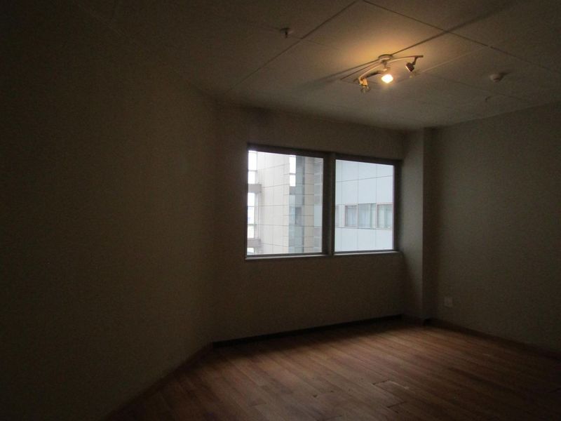 An empty bedroom featuring laminate flooring and a ceiling-mounted spotlight fixture, offering a blank canvas for potential interior design updates.