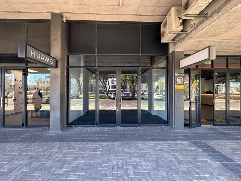Modern retail storefront with large glass display windows, aluminum framing, and paved pedestrian access area.