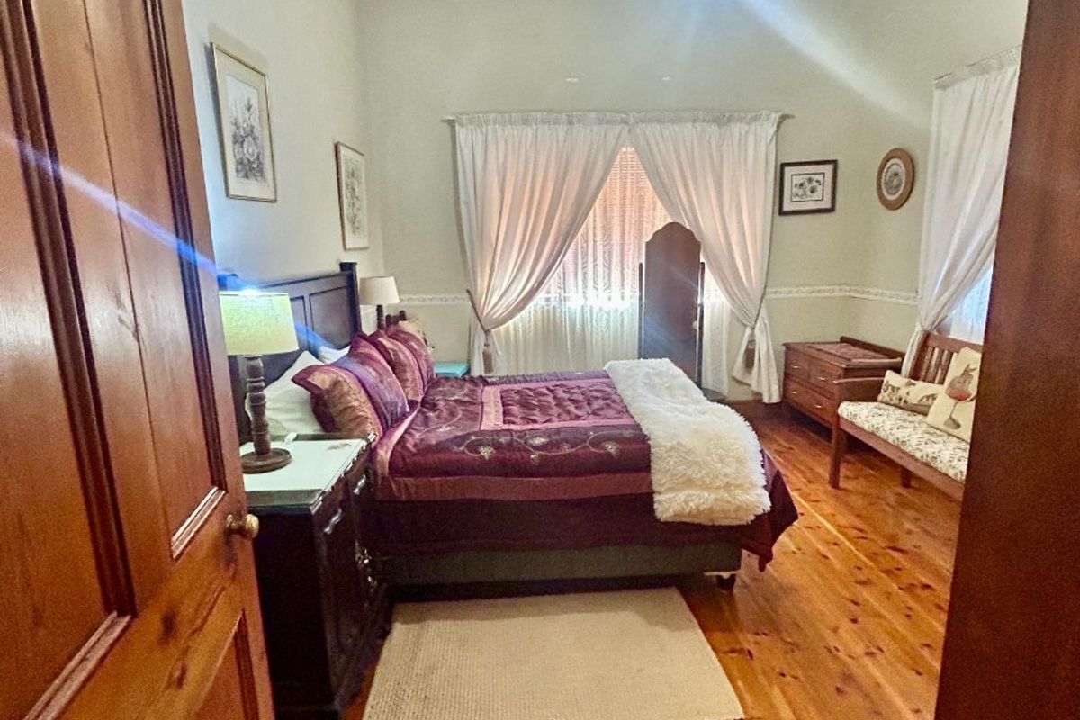 A well-maintained bedroom featuring polished timber flooring, a classic pressed metal ceiling, and traditional picture rail detailing.