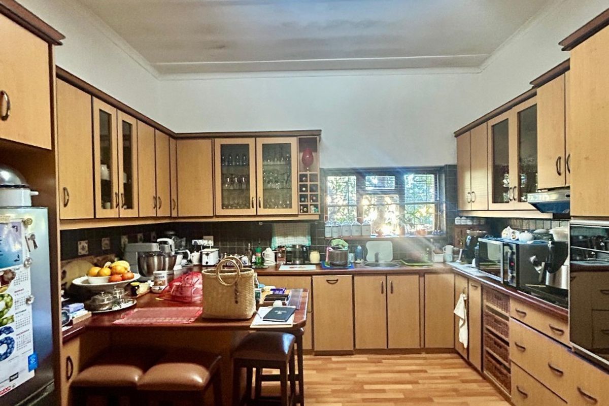 A functional kitchen featuring extensive built-in cabinetry, laminate flooring, and a tiled backsplash, offering a practical layout with integrated appliances.