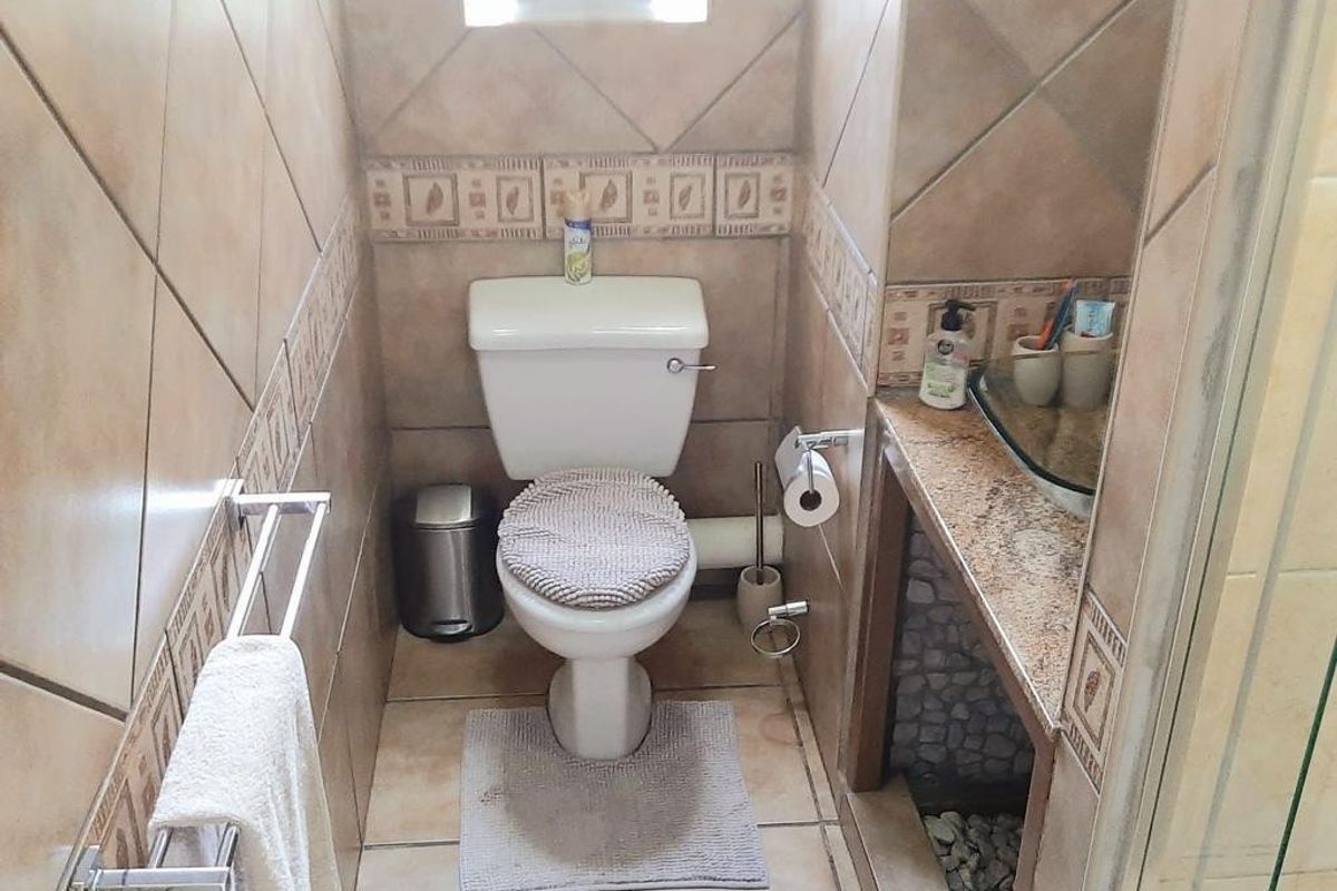 Compact bathroom featuring tiled walls with decorative borders, a standard toilet, and a vanity countertop area.