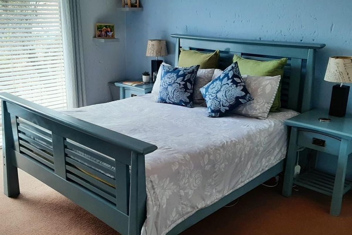 A bedroom featuring blue painted walls and venetian blinds, providing a functional space with natural light.