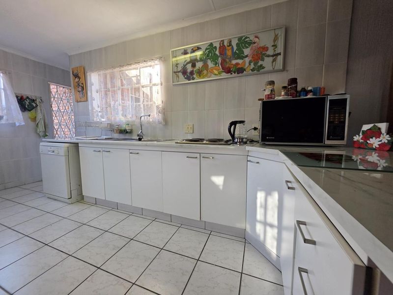 A functional kitchen featuring tiled flooring, wall-to-wall tiling, built-in cabinetry, and a built-in hob, offering a clean and practical workspace.