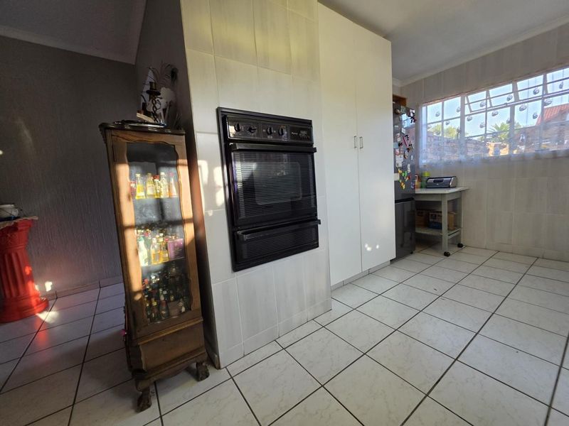 A functional kitchen area featuring a built-in double oven, tiled flooring, and ample cabinetry, offering a practical layout for daily cooking and food preparation.