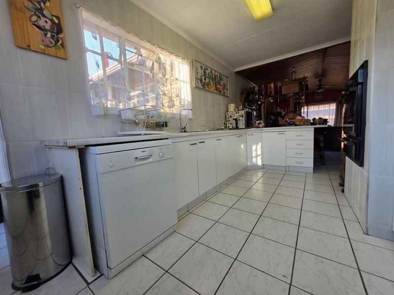 A functional kitchen featuring white cabinetry, tiled surfaces, and a built-in oven, offering a clean layout with potential for modern updates.