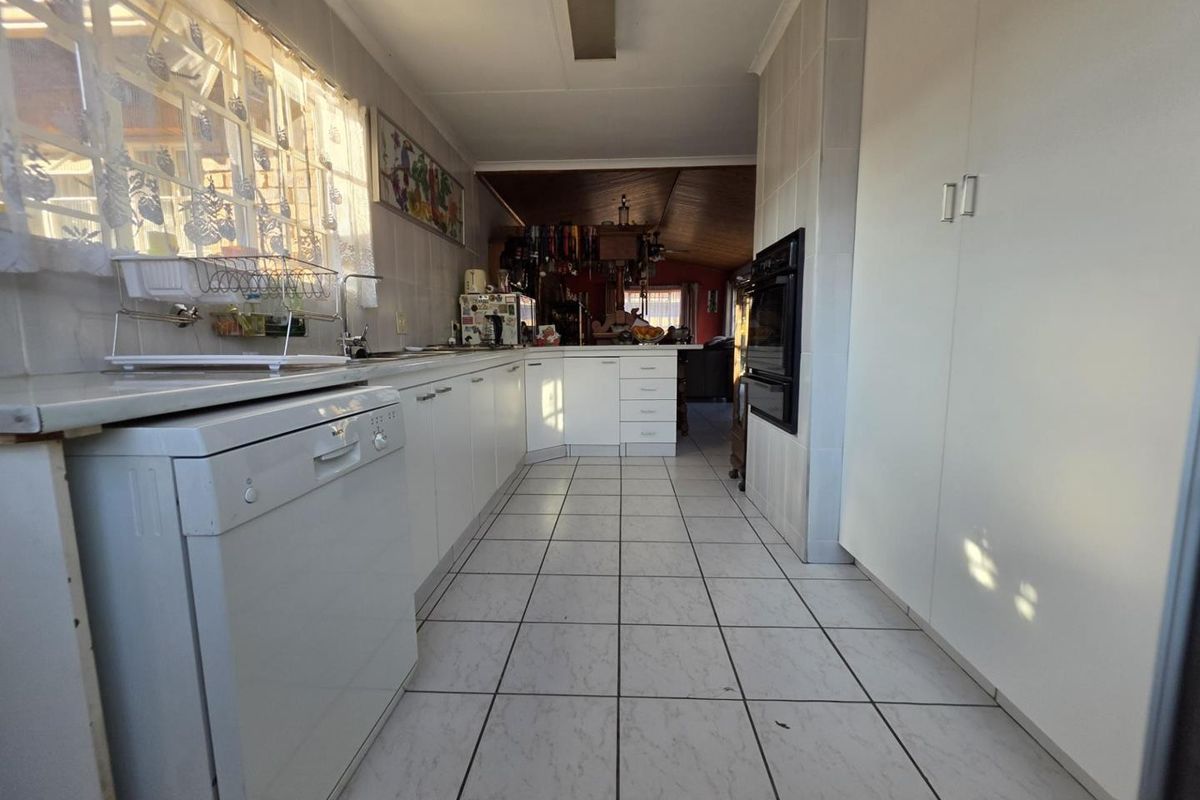 A functional kitchen featuring white cabinetry, tiled flooring, a built-in oven, and a tiled backsplash, offering a clean layout with potential for modern updates.