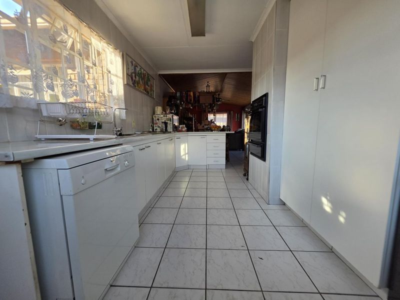 A functional kitchen featuring white cabinetry, tiled flooring, a built-in oven, and a tiled backsplash, offering a clean layout with potential for modern updates.