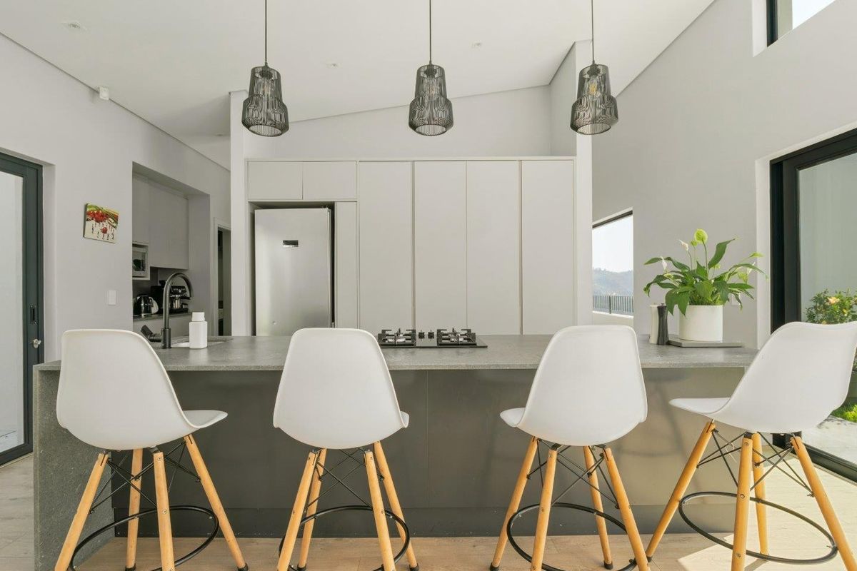 Modern kitchen featuring a large central island with stone countertops, integrated gas cooktop, sleek cabinetry, and stylish pendant lighting in an open-plan layout.