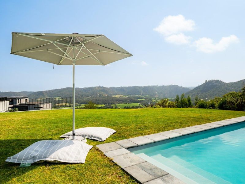 A pristine swimming pool area featuring stone coping and expansive views of the surrounding hills and landscape.