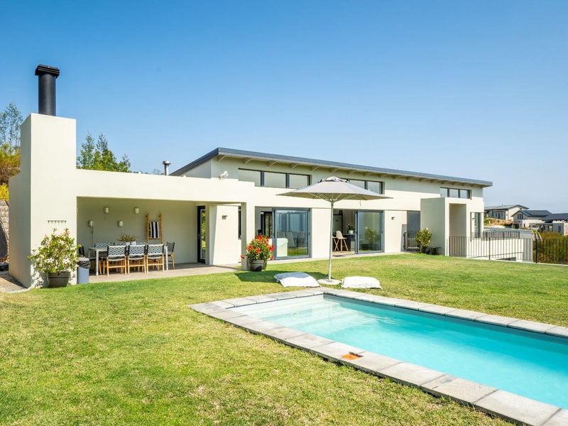 Rear view of the property featuring a covered patio with an outdoor fireplace, a swimming pool, and a well-maintained lawn.