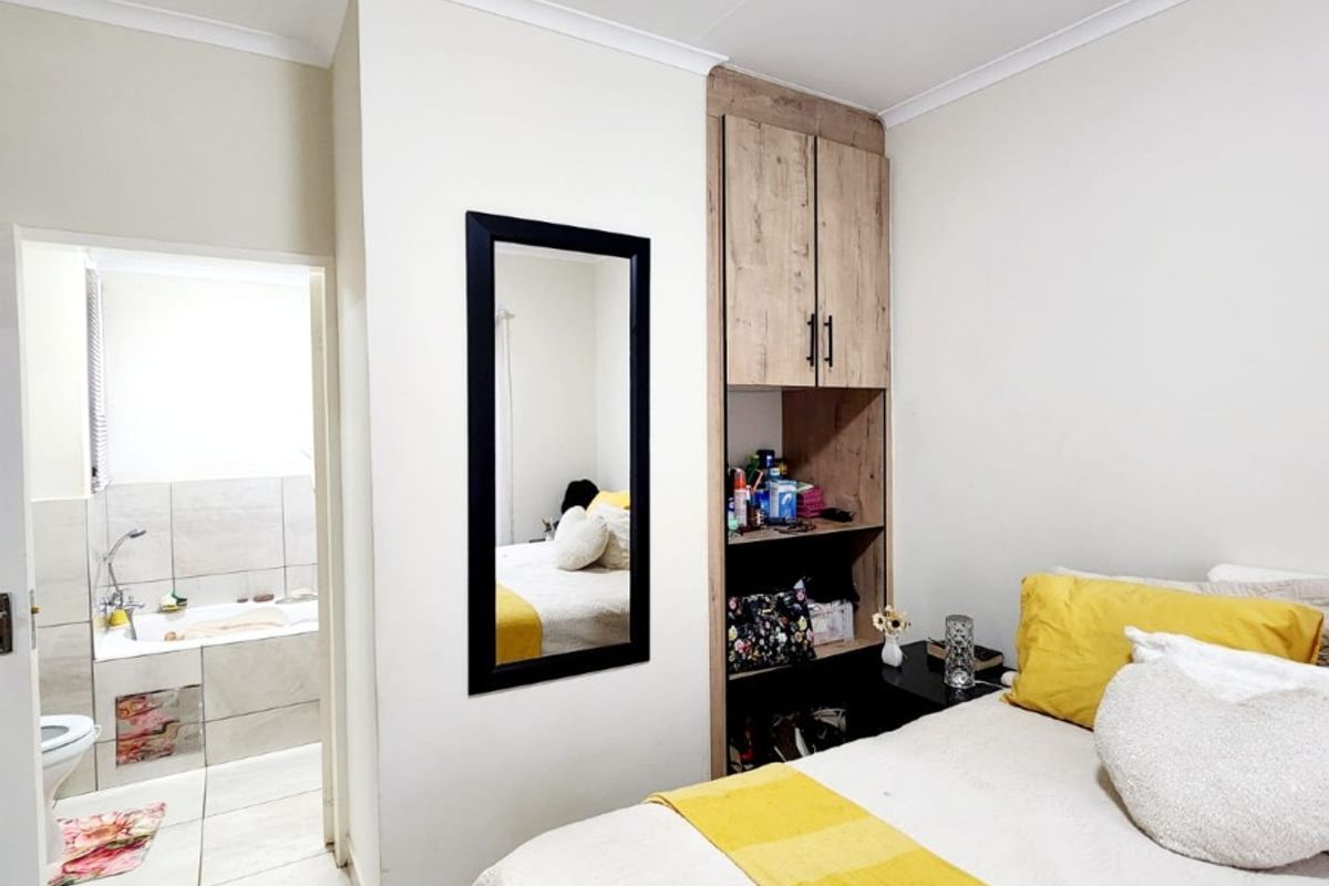 A bedroom featuring built-in cabinetry and tiled flooring, with an open-plan layout leading directly into an en-suite bathroom.