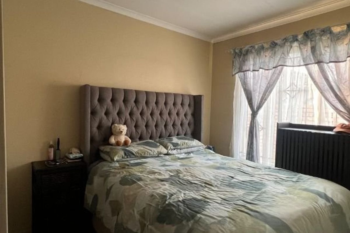 A standard bedroom featuring neutral wall paint, coving, and a window with installed curtain rails.