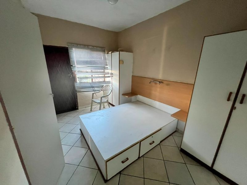 A bedroom featuring tiled flooring, built-in cupboards, and a headboard. The room requires cosmetic updates to improve its overall condition and appeal.