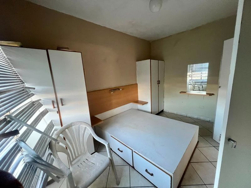 A bedroom featuring built-in cupboards, a built-in headboard, and tiled flooring. The room requires cosmetic updates to improve its overall condition and appeal.