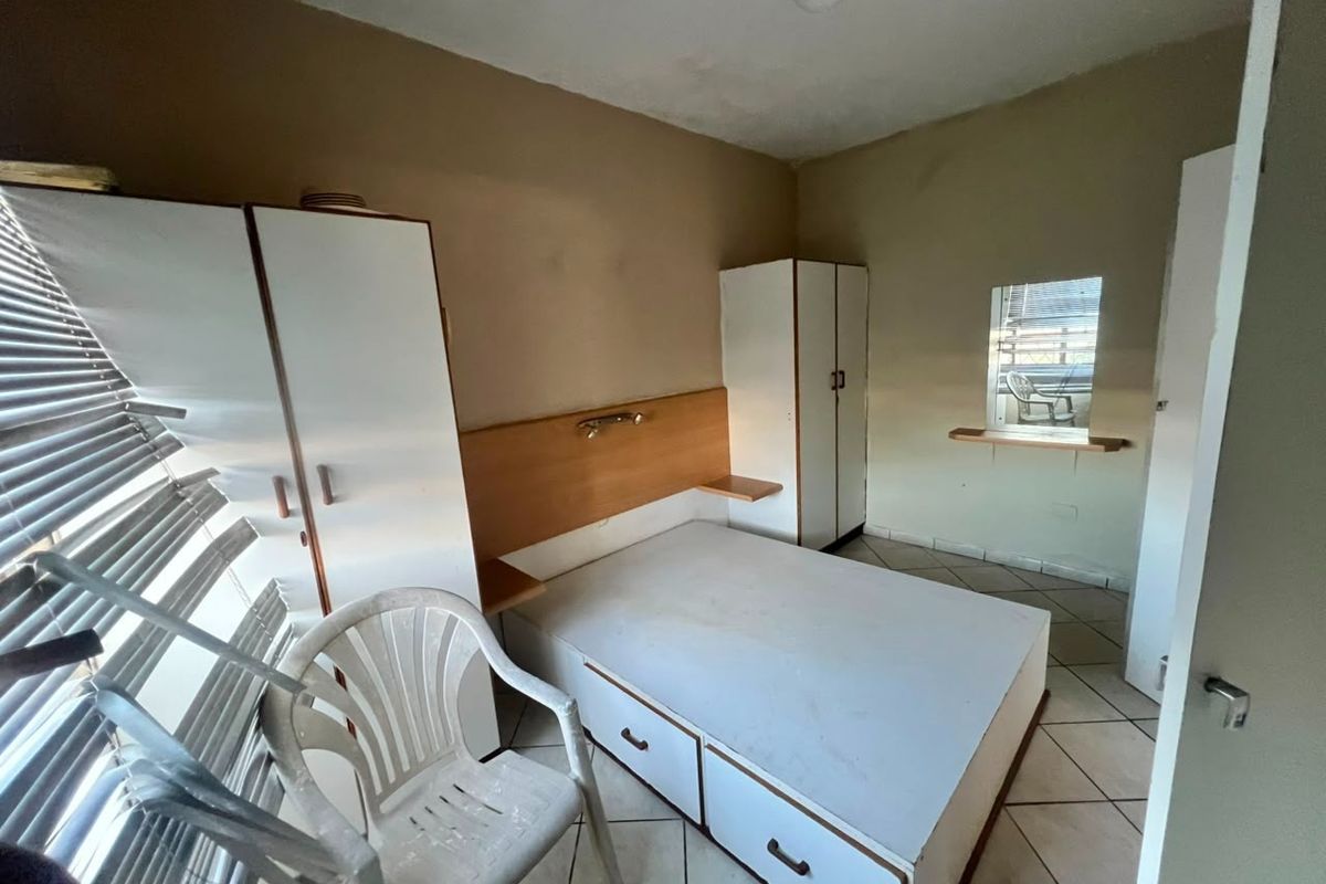 A bedroom featuring built-in cupboards, a built-in headboard, and tiled flooring. The room requires cosmetic updates to improve its overall condition and appeal.