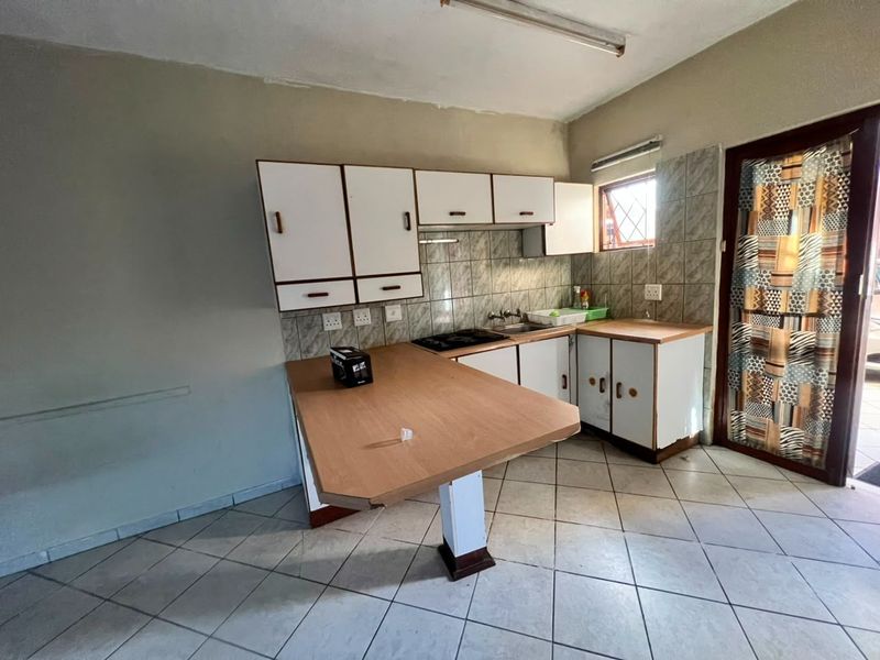 A dated kitchen featuring built-in cabinetry, laminate countertops, a built-in hob, and tiled flooring, offering potential for a modern renovation.