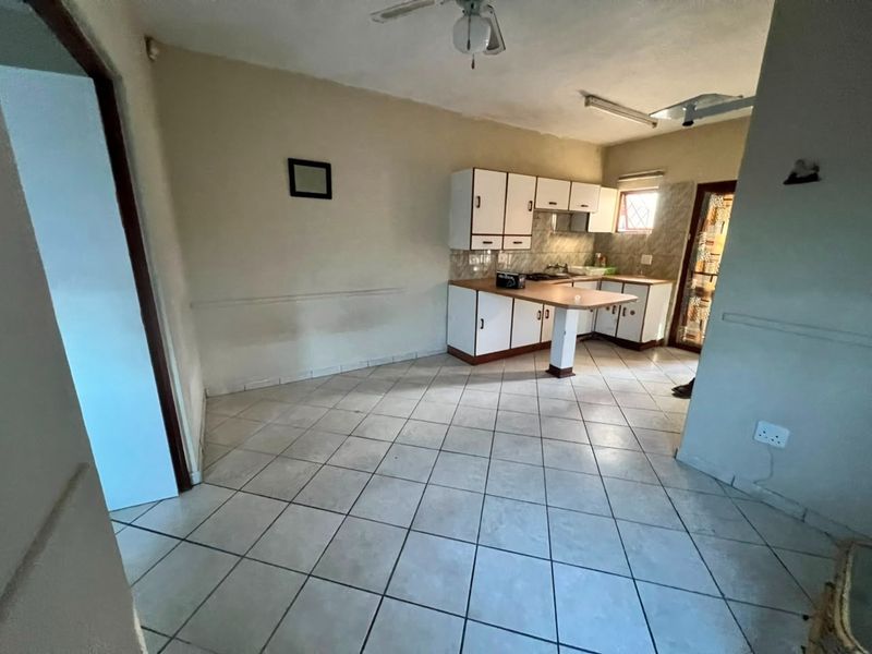 A dated kitchen featuring built-in cabinetry, a breakfast bar, and tiled flooring, offering a blank canvas for potential renovation and modernization.
