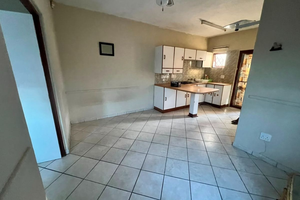 A dated kitchen featuring built-in cabinetry, a breakfast bar, and tiled flooring, offering a blank canvas for potential renovation and modernization.