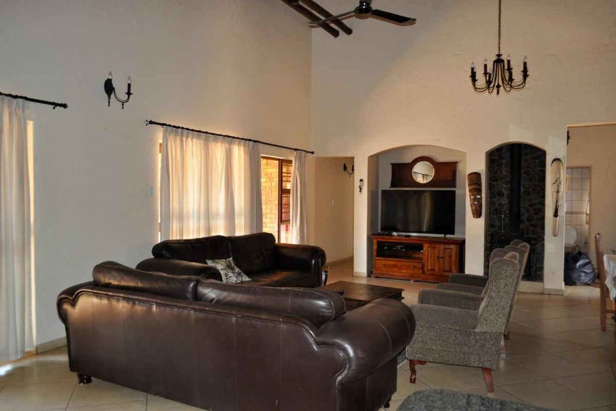 Spacious living room featuring a high vaulted ceiling, ceiling fan, tiled flooring, and a distinctive arched alcove with a stone fireplace.