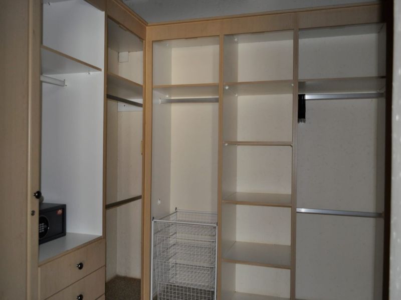 A walk-in closet or bedroom wardrobe featuring extensive built-in cabinetry, shelving, hanging rails, and a secure built-in safe.