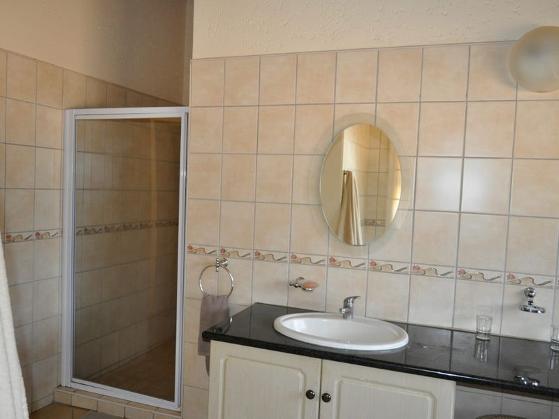 A functional bathroom featuring a vanity with a granite countertop, drop-in sink, and a separate shower enclosure with tiled wall finishes.