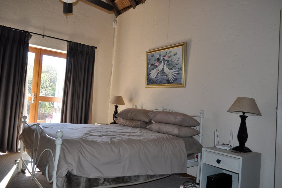 A bedroom featuring a vaulted ceiling with exposed rafters, a ceiling fan, and a glass panel door providing access to the outdoors.