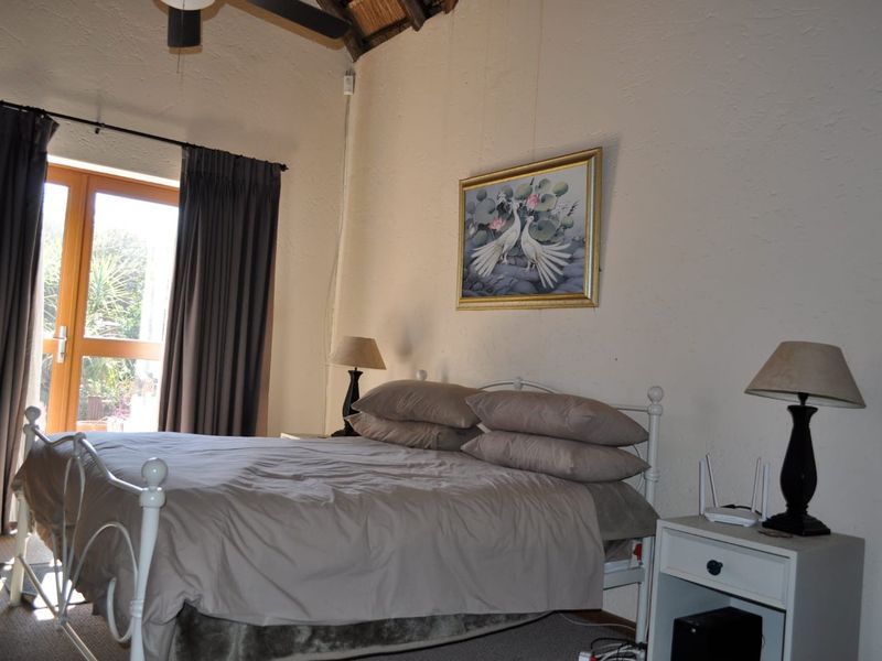 A bedroom featuring a vaulted ceiling with exposed rafters, a ceiling fan, and a glass panel door providing access to the outdoors.