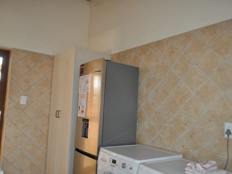 A functional laundry area featuring tiled splashbacks and built-in cabinetry, providing practical utility space for household tasks.