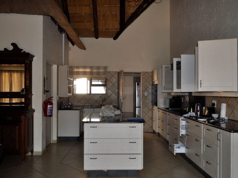 Spacious kitchen featuring a central island, granite countertops, ample built-in cabinetry, and a high-volume ceiling with exposed timber rafters.