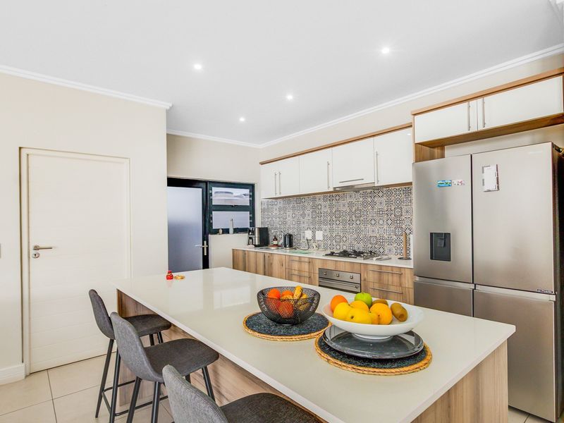 Modern kitchen featuring a central island with stone countertops, built-in cabinetry, gas hob, oven, and stylish patterned tile backsplash.