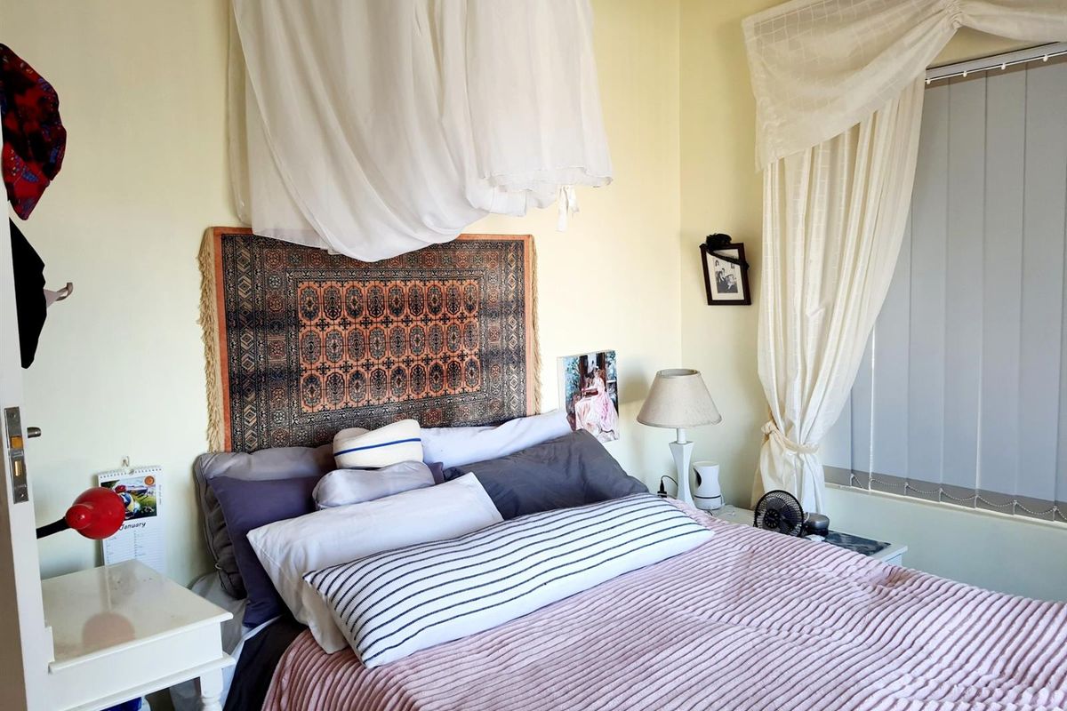 A bedroom featuring neutral wall finishes and vertical blinds, providing a functional space for rest.