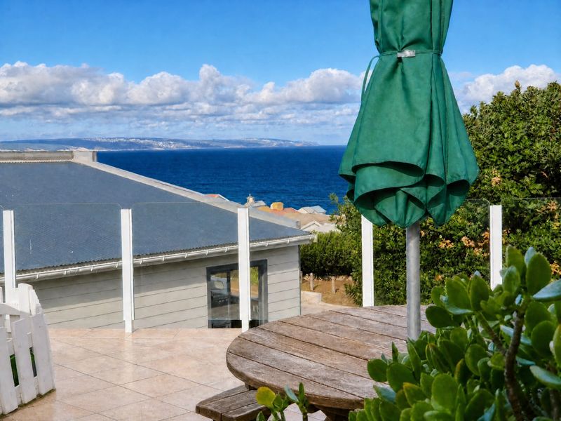 An elevated patio area featuring tiled flooring and a glass balustrade, offering expansive ocean views.
