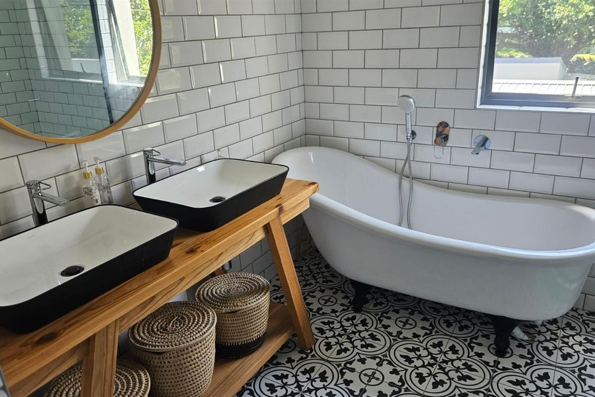 Modern bathroom featuring a freestanding bathtub, double vanity with vessel sinks, subway tile walls, and decorative patterned floor tiles.