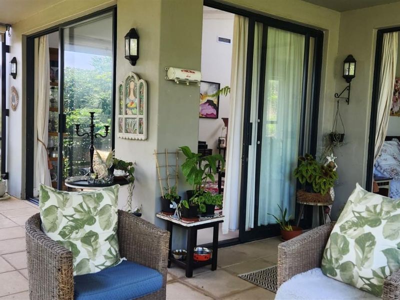 A covered patio area featuring tiled flooring, wall-mounted lighting, and multiple sliding glass door access points to the interior living spaces.