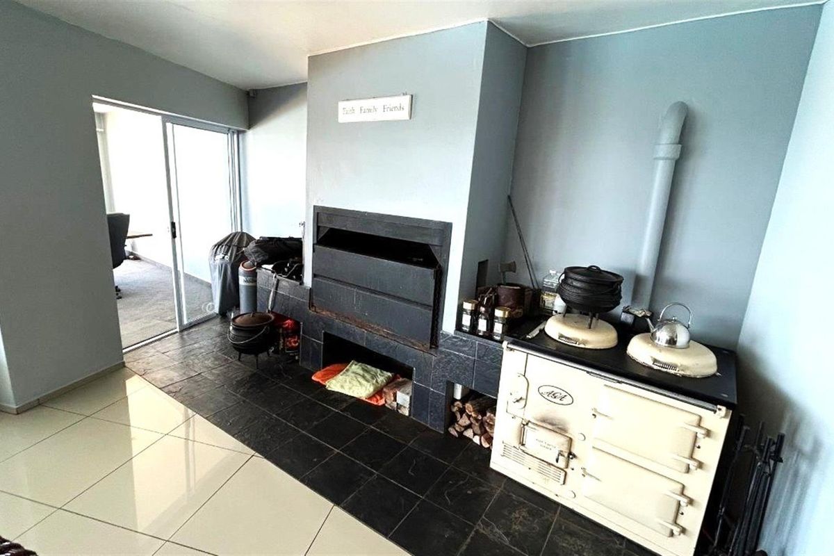 Indoor entertainment area featuring a built-in braai and a classic AGA stove, with tiled flooring and sliding door access to the exterior.