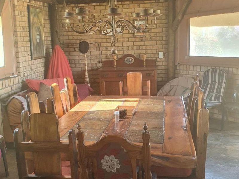 Rustic dining area featuring a traditional thatched roof, exposed brick walls, and timber structural elements, creating a warm and authentic farm-style atmosphere.